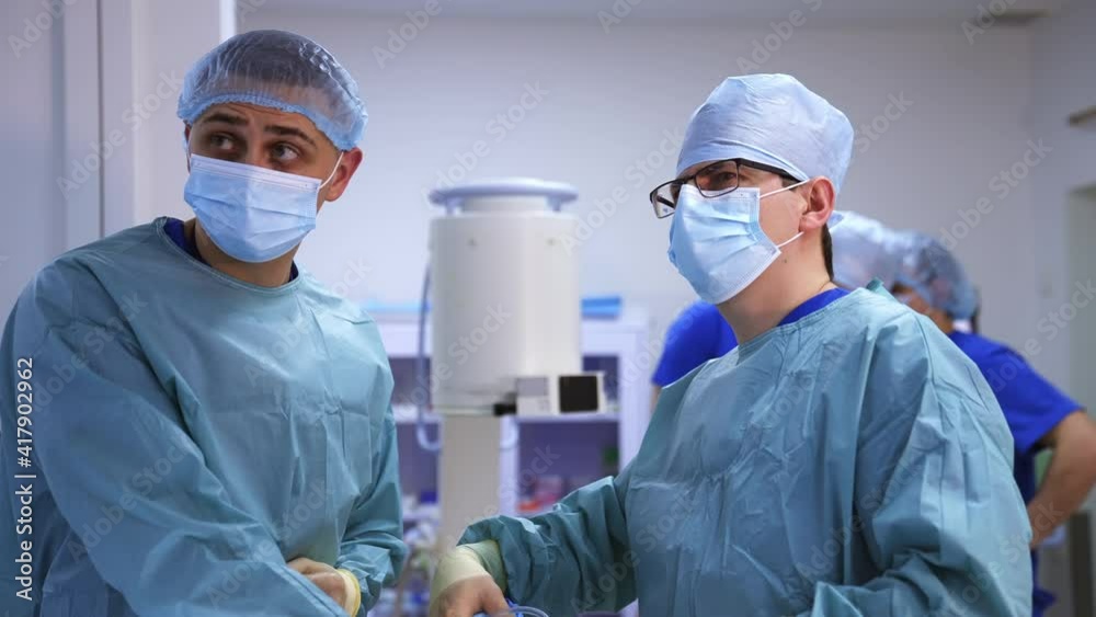 Medical team performing surgical operation in bright modern surgery room. Operating theatre. Modern equipment in clinic. Emergency room. Medical team performing surgical operation in bright modern surgery room. Operating theatre. Modern equipment in clinic. Emergency room.