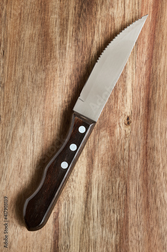 Kitchen knife for steak and meat on wooden board, close up