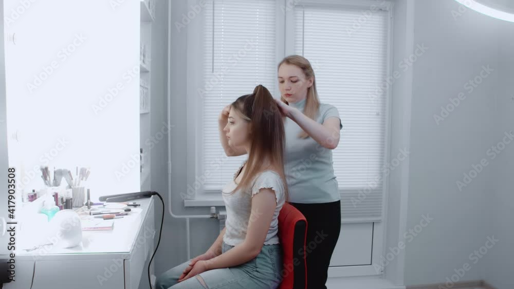The hairdresser is slowly combing the hair of a beautiful model in the beauty salon. Beauty concept. Close-up . The hairdresser is slowly combing the hair of a beautiful model in the beauty salon. Beauty concept. Close-up .