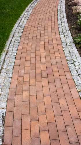 Pavement with cobblestones gray and red, among the grass