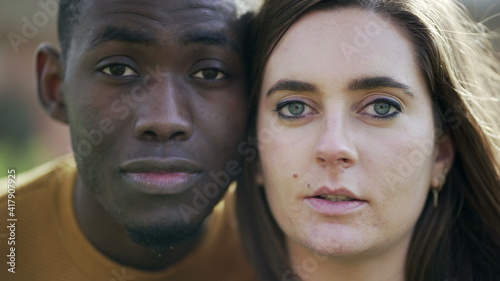 African man and white girl opening eyes together. Interracial couple looking at camera