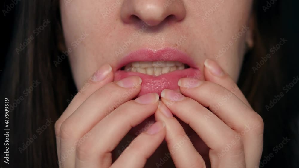The woman covers her mouth with her hands and is very nervous. Lips and mouth of an attractive woman The woman covers her mouth with her hands and is very nervous. Lips and mouth of an attractive woman