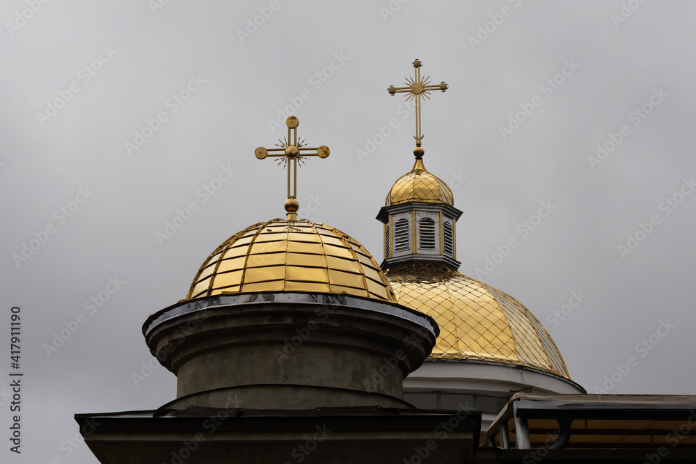 Two yellow domes of the church. Against the backdrop of a cloudy sky.