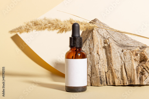 Cosmetic jar with cream, serum or organic essential oil for the face and body, against the background of a log and hard shadows. The concept of a beauty salon and natural cosmetics.