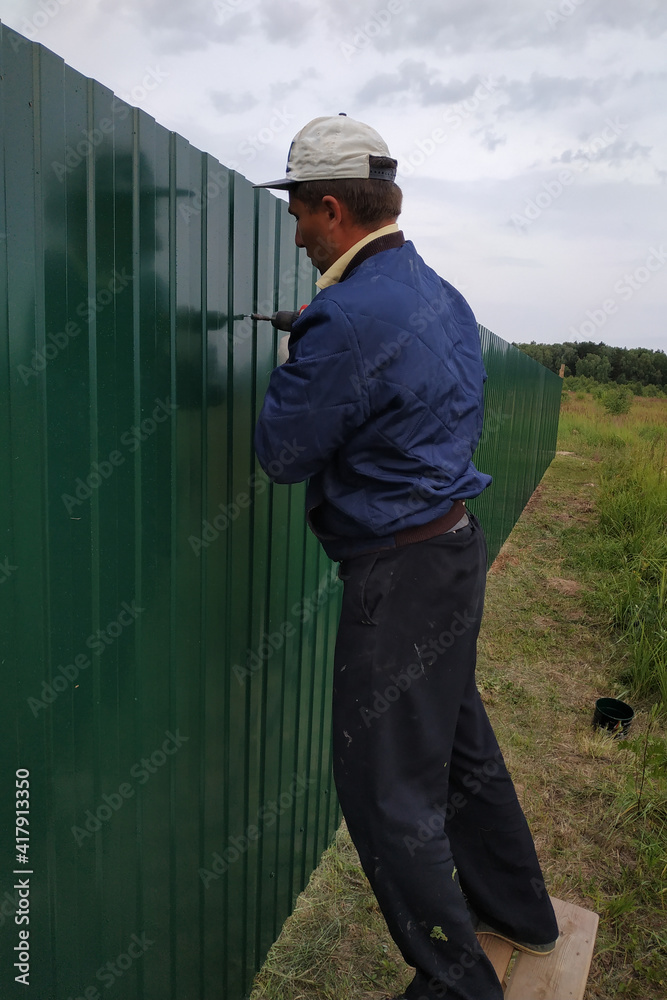 Fastening of a metal sheet to a framework of a fence by means of the screw-driver, screwing of screw-drivers in a fence.