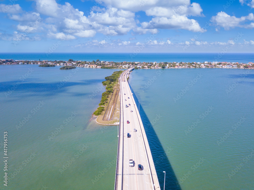 Bridge over the bay. Spring break or Summer vacations in Florida. Traffic on Beach Road. Ocean or Gulf of Mexico. Tropical nature. Aerial view. 