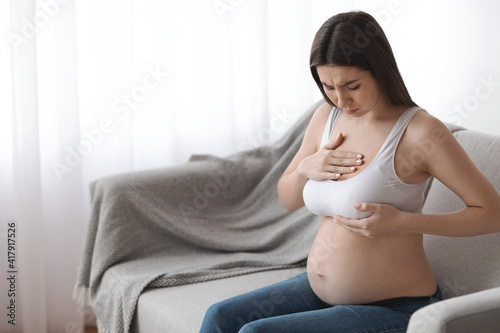 Millennial pregnant lady having painful feelings in breast area, suffering discomfort