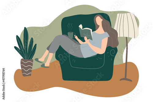 Faceless portrait of a young girl sitting in the armchair relaxing, drinking hot tea and reading, concept of cozy staying home