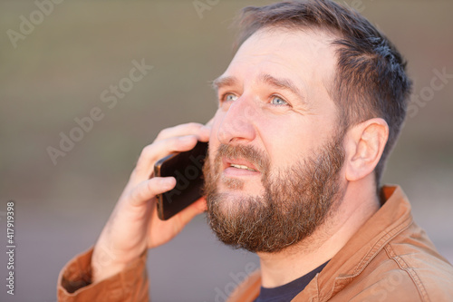 portrait of an adult man who is talking on the phone and looking up