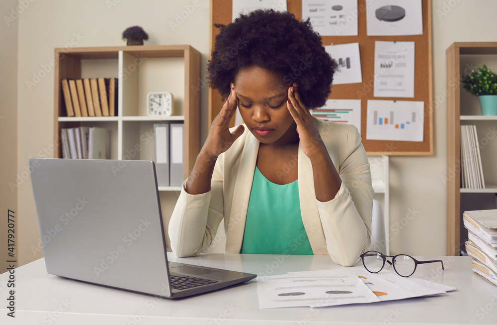 © Studio Romantic - Fatigue, exhaustion and tension at work. Tired exhausted overworked african american millennial woman feeling strong headache or dizziness in need of rest sit front of laptop at desk in office