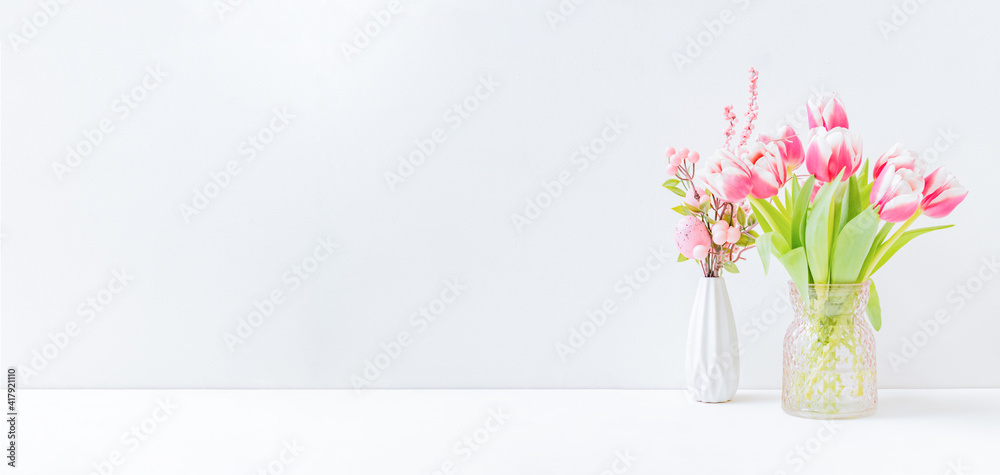 Home interior with easter decor. Pink tulips in a vase on a light background Home interior with easter decor. Pink tulips in a vase on a light background