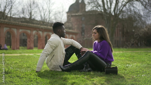  Interracial couple hanging together outside sitting on grass at park