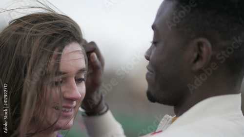 Interracial couple outside. Boyfriend caressing girlfriend hair