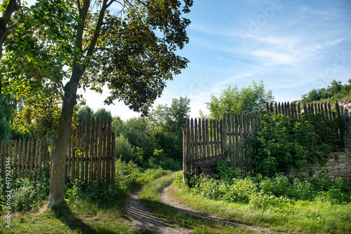 fence in the village, green trees and bushes at the gate in the village, beautiful countryside landscape