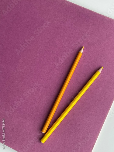 Colored pencils on purple paper album on white table. Artist, art and hobby. Drawing and painting