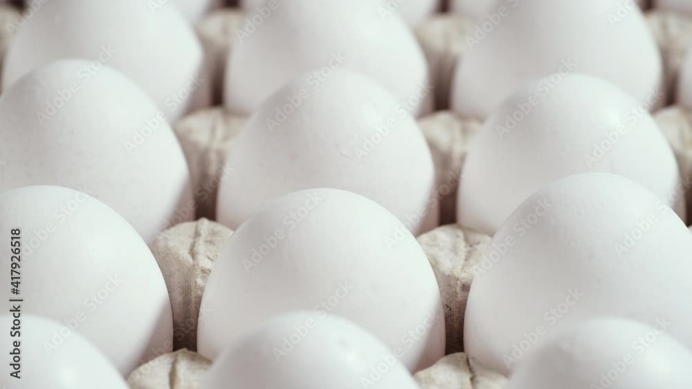 Lots of fresh raw chicken eggs in a cardboard box, rotation shot, Chicken white fresh raw eggs in an egg container