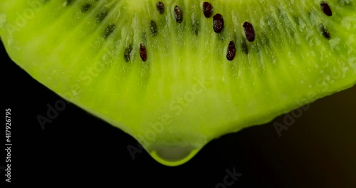 water pouring on kiwi slice over black background. High quality 4k footage