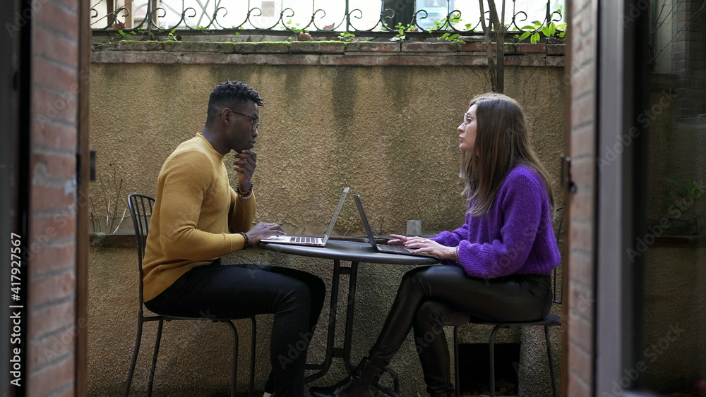 Fototapeta premium Young diverse couple working from home using laptop computer