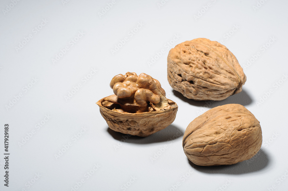 Three large walnuts in the shell and the kernel of one nut on a gray background Three large walnuts in the shell and the kernel of one nut on a gray background