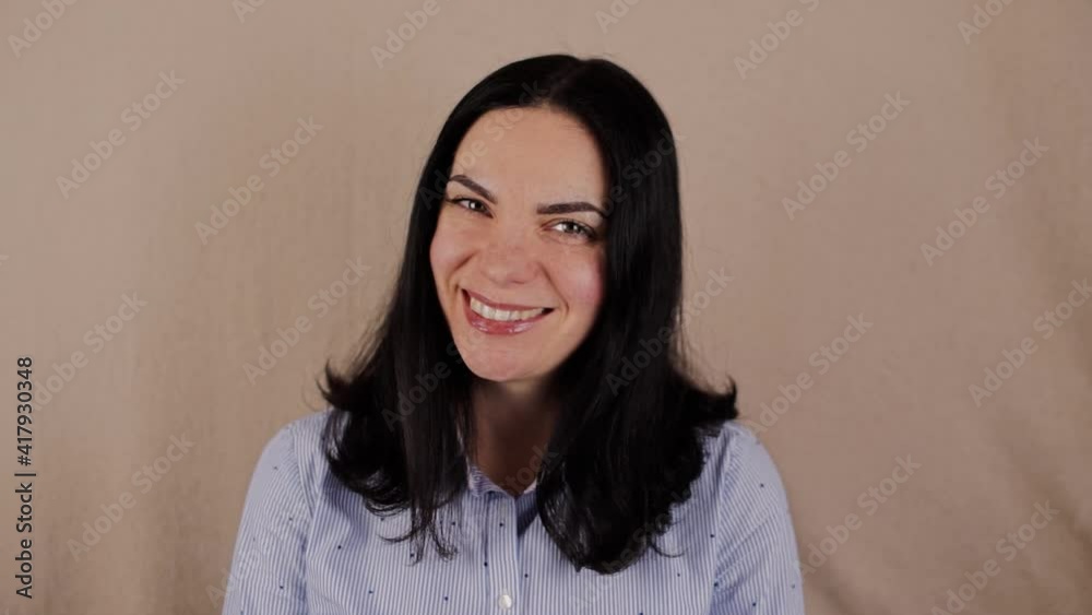 a woman with dark hair in shirt smiling on background a woman with dark hair in shirt smiling on background