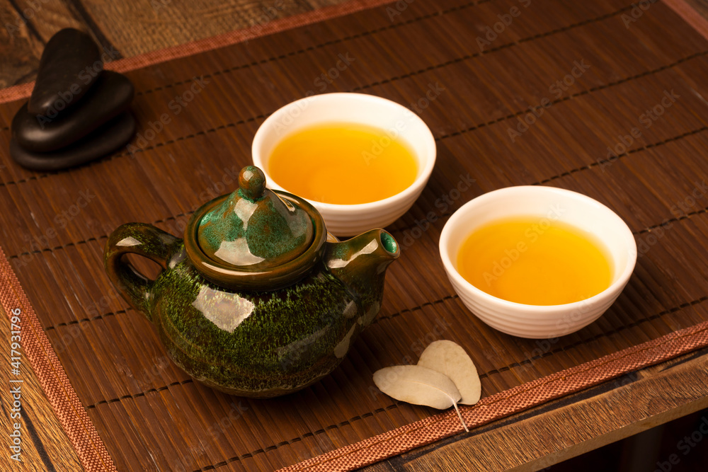 Bellied teapot on wooden table with two cups of tea Bellied teapot on wooden table with two cups of tea