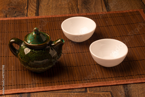 Tea in bellied teapot on wooden table with two white empty cups