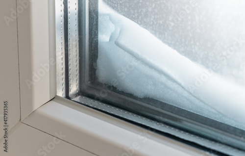 The window sill is covered with snow at the window outside