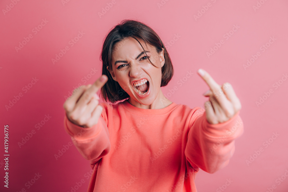 Woman wearing casual sweater on background showing middle finger doing bad expression, provocation and rude attitude Woman wearing casual sweater on background showing middle finger doing bad expression, provocation and rude attitude