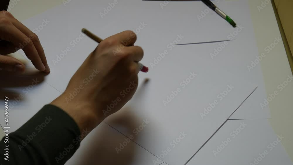 The man's hand writes the month of July on with a brush and gouashe. The man writes July.