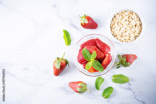 Oatmeal porridge with milk and fresh strawberries in a glass