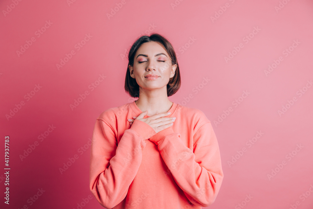Woman wearing casual sweater on background smiling with hands on chest with closed eyes and grateful gesture on face Woman wearing casual sweater on background smiling with hands on chest with closed eyes and grateful gesture on face