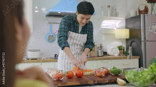 Husband slicing vegetables to prepare breakfast. With a young wife supporting him In a romantic atmosphere