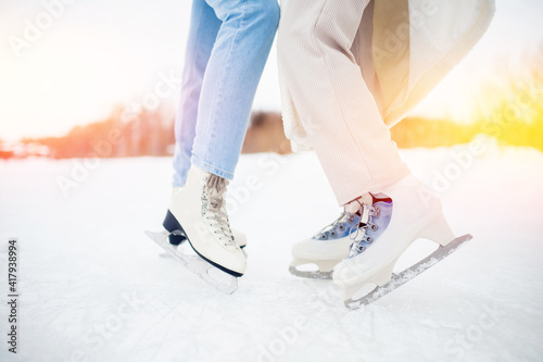 Closeup two women wearing white ice skates on winter sunset background