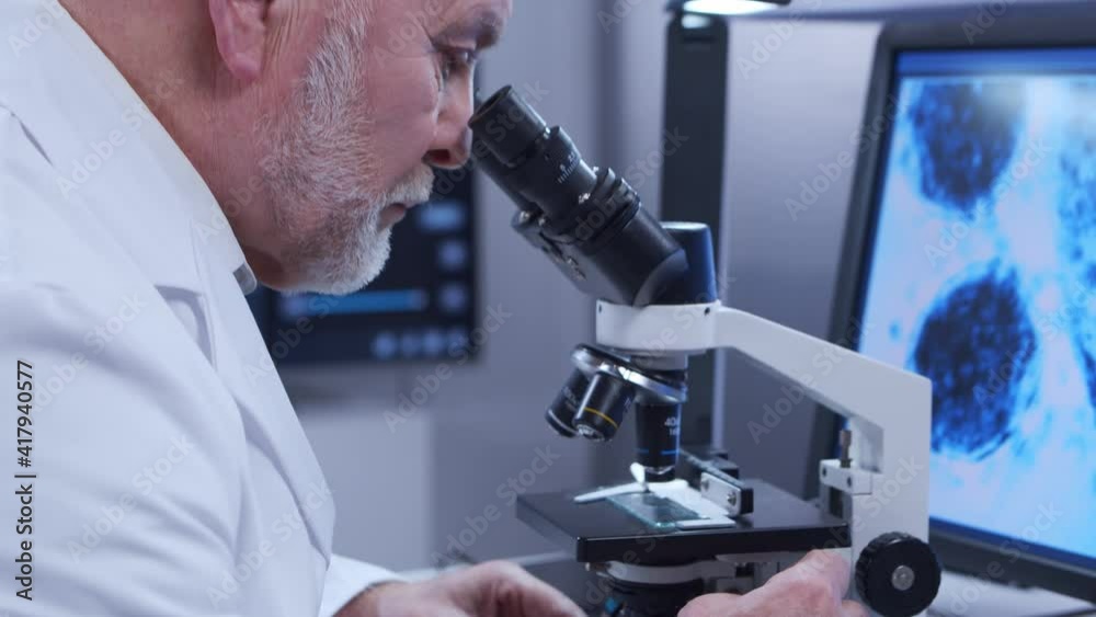 Elderly professor is doing a science experiment in a modern laboratory. Genetic engineers workplace. The concept of science, medicine and vaccine development. Elderly professor is doing a science experiment in a modern laboratory. Genetic engineers workplace. The concept of science, medicine and vaccine development.
