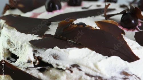 una bella torta foresta nera con le foglie di cioccolato immerse nella bianca copertura di panna e amarene, una vista ravvicinata di una torta  photo