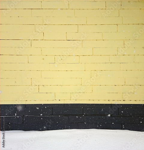 yellow background with black and white brick wall with snow