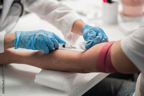 A nurse in the lab takes a blood test from a vein  a close-up plan without a face.