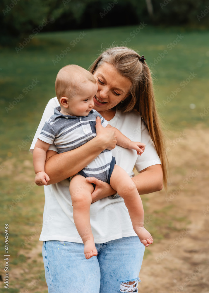 Fototapeta premium mother holding and kissing son outside in summer