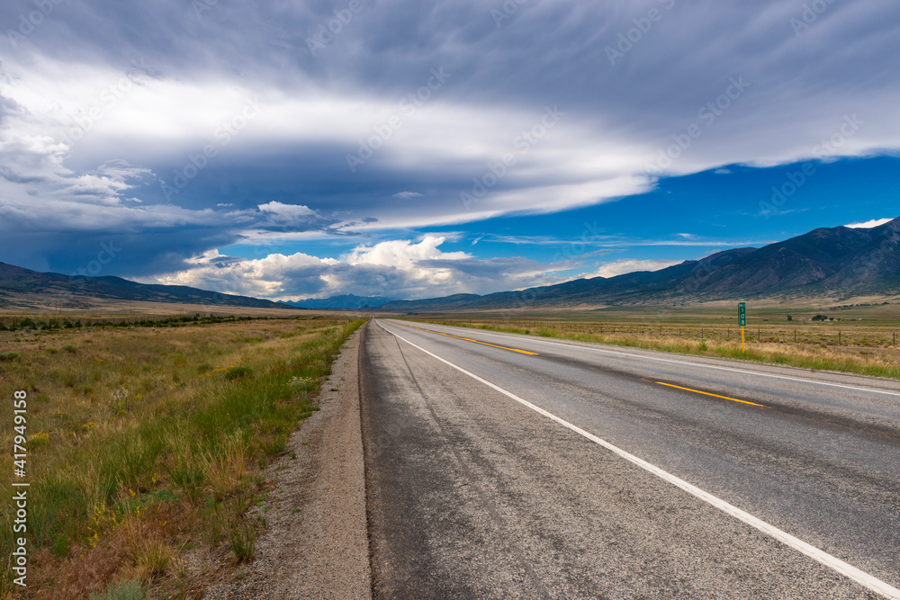 Scenic view of an empty road with mountains on the background, in the State of Colorado, USA; Concept for travel and road trip in the USA Scenic view of an empty road with mountains on the background, in the State of Colorado, USA; Concept for travel and road trip in the USA