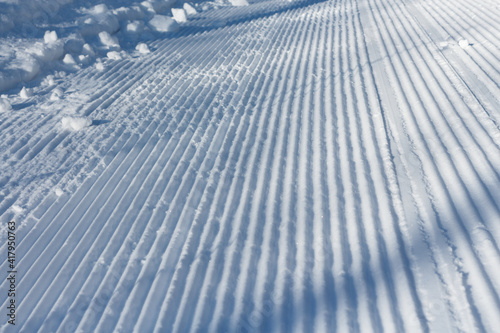 Traces in the form of stripes in the snow. Snow groomer print, close-up.