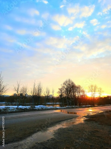 Spring sunset with sun glare on wet asphalt.