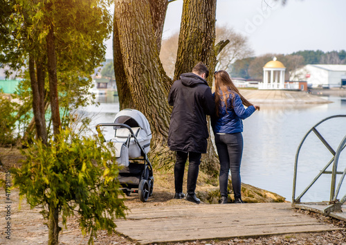 A married couple rolls a baby stroller in a city Park 