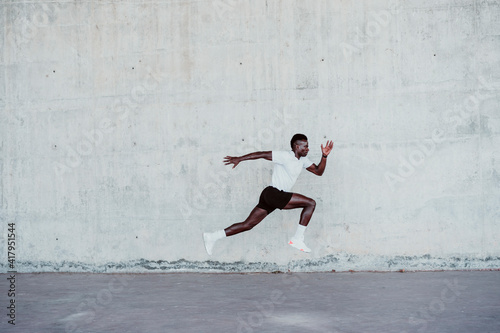 Determinant sportsman jumping by wall photo