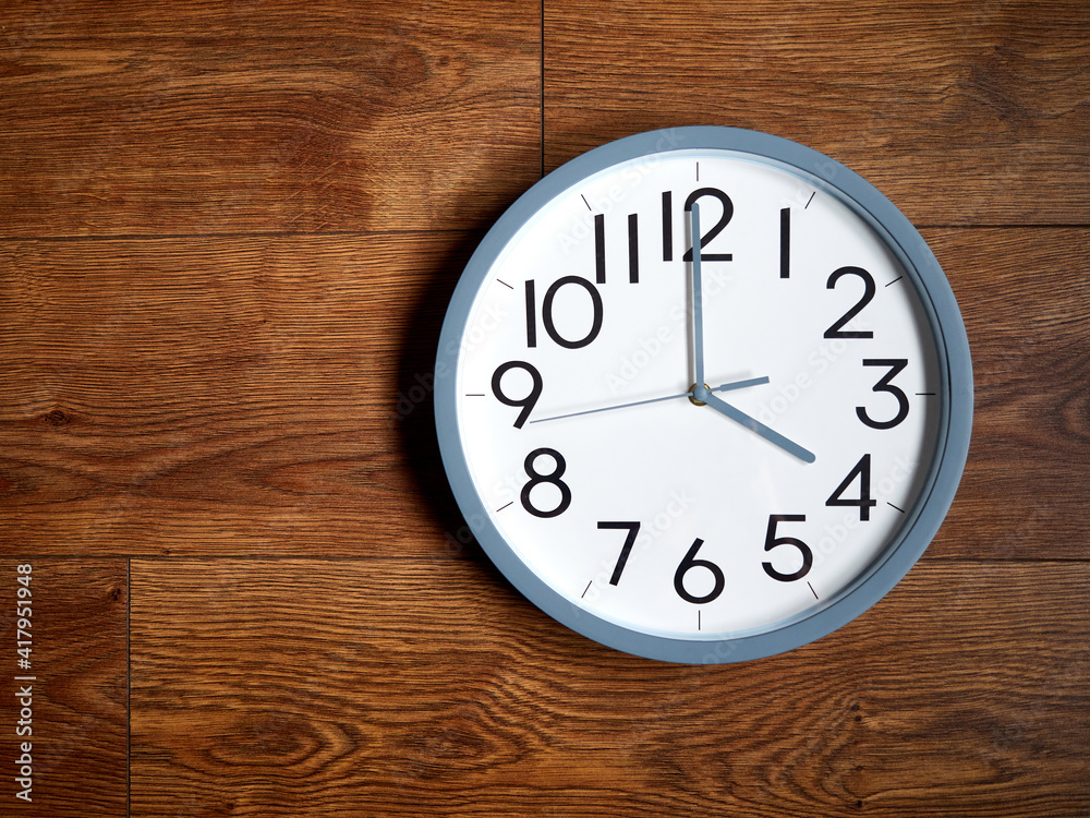 white round analog clock on wooden background white round analog clock on wooden background