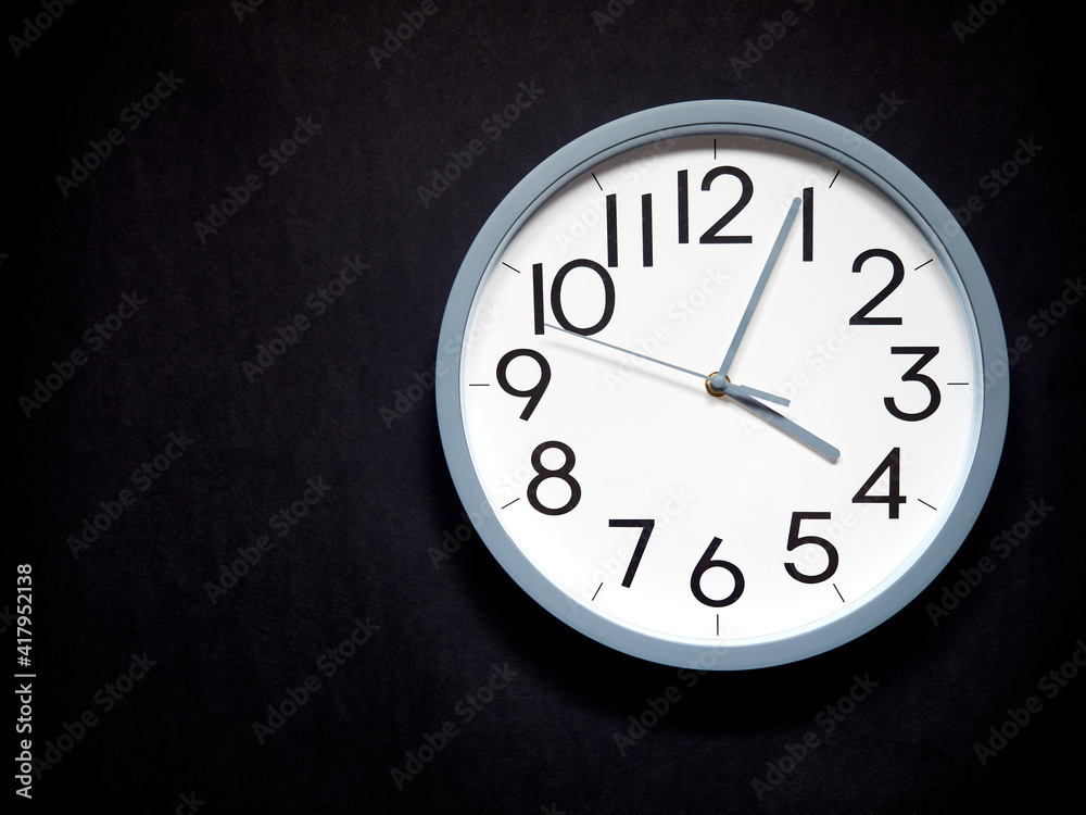 white round analog clock on black background white round analog clock on black background