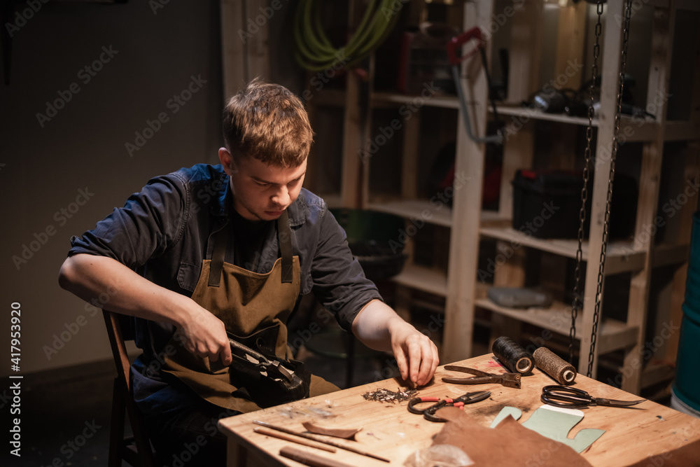 a young master in the manual production of shoes in his workshop is working on creating shoes a young master in the manual production of shoes in his workshop is working on creating shoes