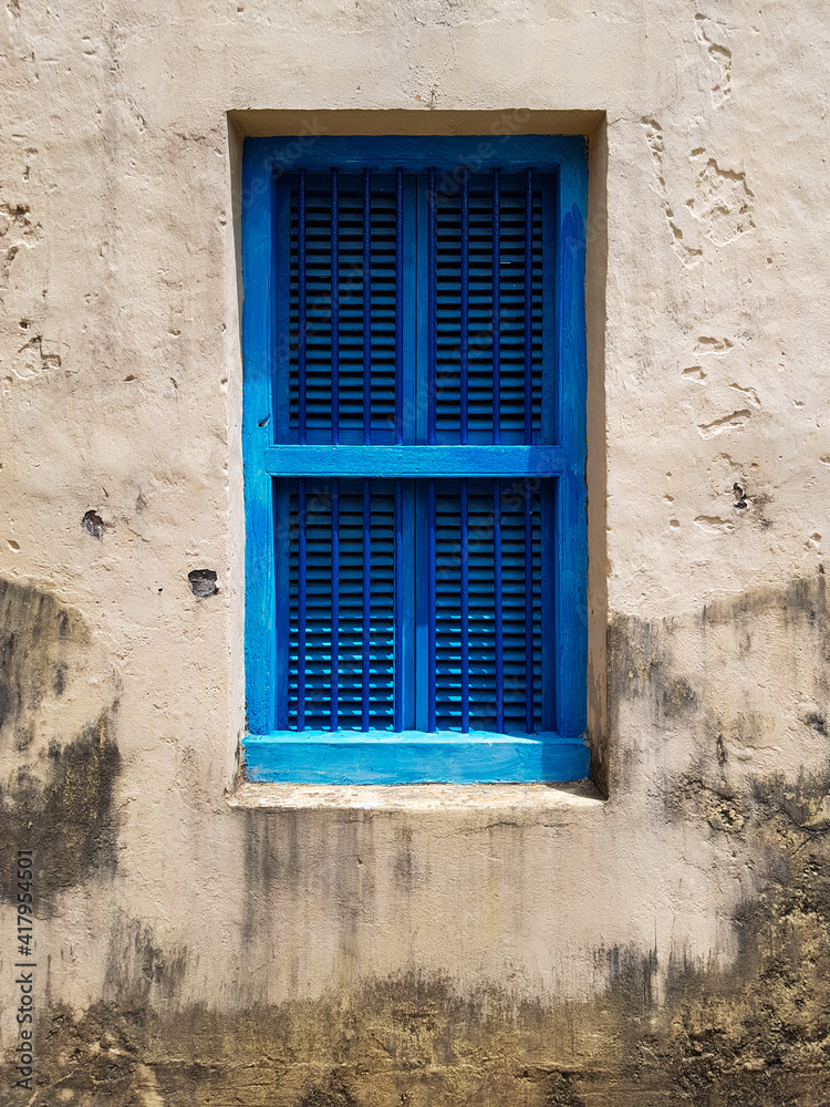 closed blue window with shutters in the window opening of an old building or house, a fragment of the facade, texture