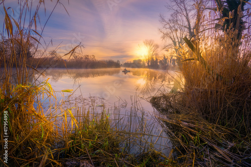 Fisherman in a dingy in river at sunrise, Veneto, Italy