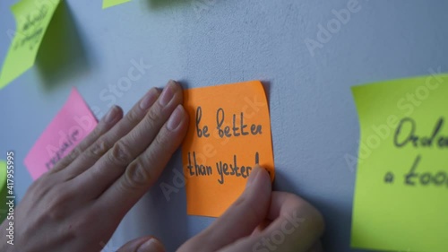 Female hands are gluing a sign reading be better than yesterday. Concept: motivation and striving to be better 