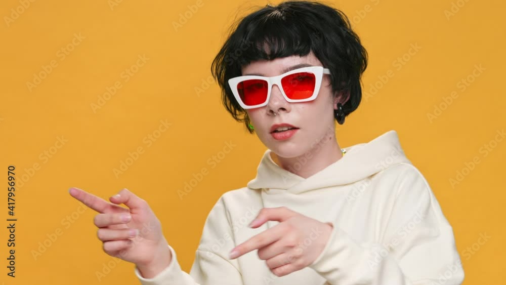Happy Teenage Girl Dancing and Singing on Yellow Background with Piercings sunglasses, Smiling, Rhythmically Moving her Hands Thumbs Up in Front of Camera Funny Dancing. Positive Emotions. Freedom Happy Teenage Girl Dancing and Singing on Yellow Background with Piercings sunglasses, Smiling, Rhythmically Moving her Hands Thumbs Up in Front of Camera Funny Dancing. Positive Emotions. Freedom
